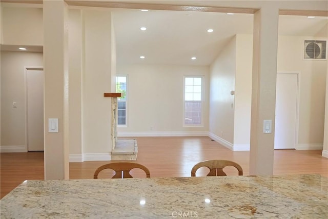 interior space with baseboards, visible vents, light stone countertops, light wood-style floors, and recessed lighting