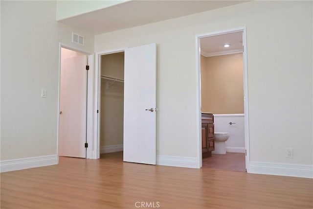 unfurnished bedroom with visible vents, baseboards, a closet, light wood finished floors, and ensuite bath