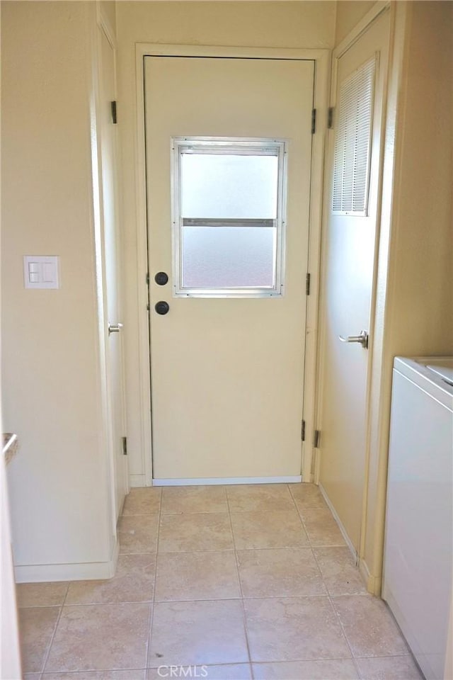 doorway to outside with baseboards, washer / clothes dryer, and light tile patterned flooring