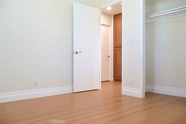 unfurnished bedroom featuring light wood-style flooring, baseboards, and a closet