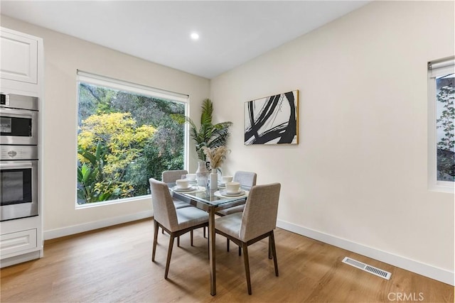 dining area featuring light wood-type flooring, plenty of natural light, visible vents, and baseboards