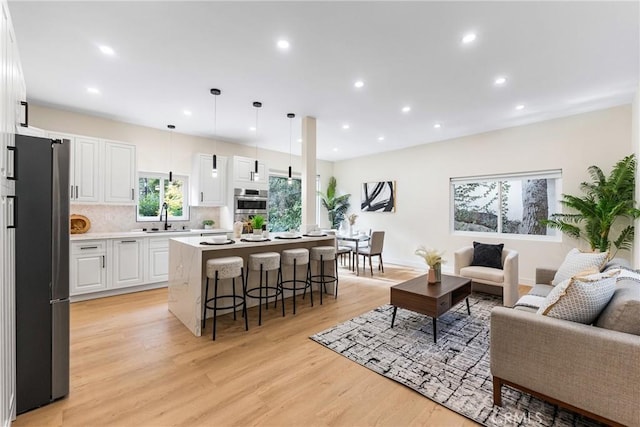 living area featuring recessed lighting, baseboards, and light wood finished floors