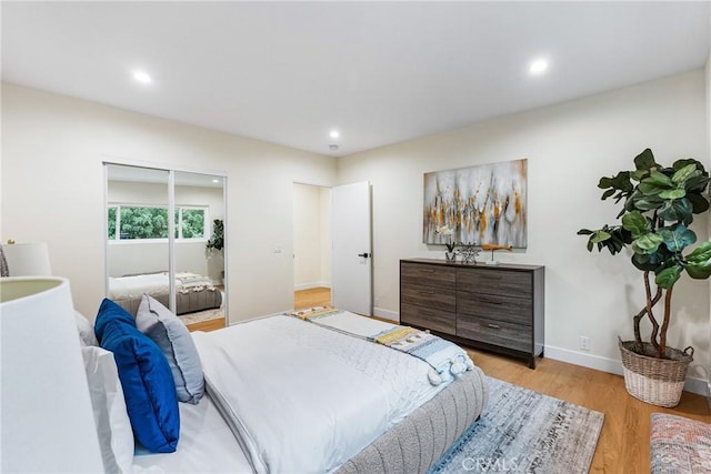 bedroom with light wood-type flooring, baseboards, a closet, and recessed lighting