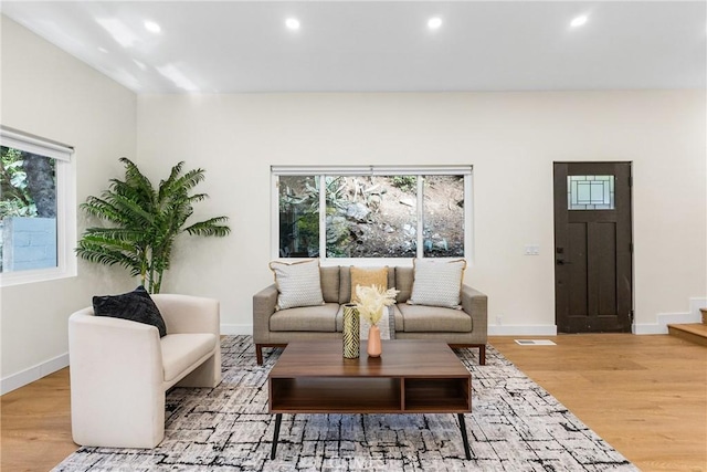 living area featuring baseboards, light wood-type flooring, visible vents, and recessed lighting