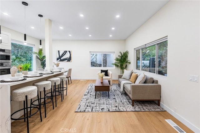 living area with recessed lighting, baseboards, visible vents, and light wood finished floors