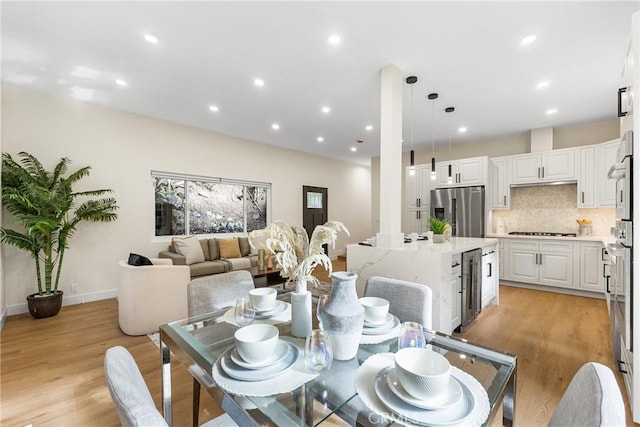 dining area featuring recessed lighting, beverage cooler, baseboards, and light wood finished floors