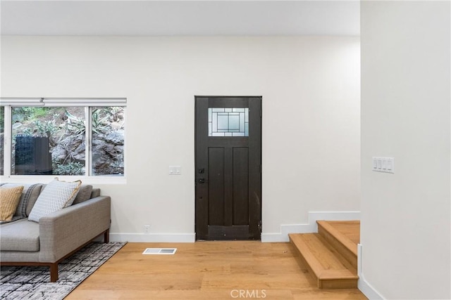 foyer featuring baseboards, stairs, visible vents, and light wood-style floors