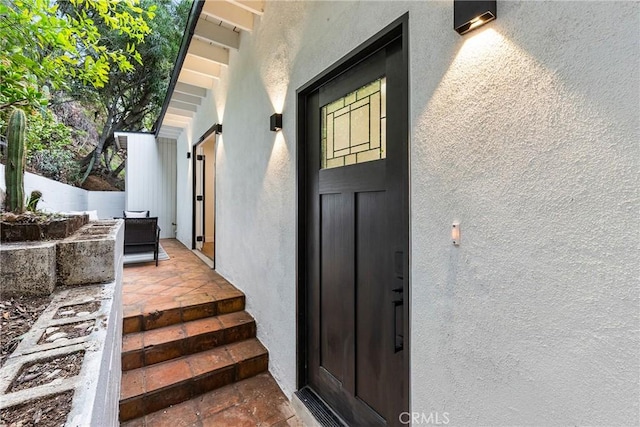 view of exterior entry featuring fence and stucco siding