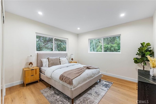 bedroom featuring light wood finished floors, multiple windows, and baseboards