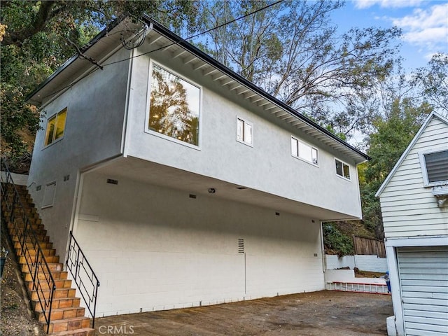 view of side of home featuring stairway and stucco siding