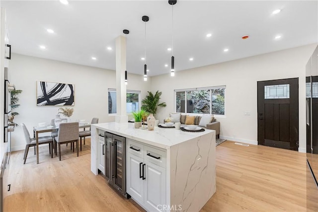 kitchen featuring light stone counters, wine cooler, light wood-style flooring, and white cabinets