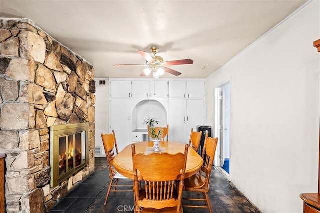 dining area with a ceiling fan, visible vents, and a fireplace