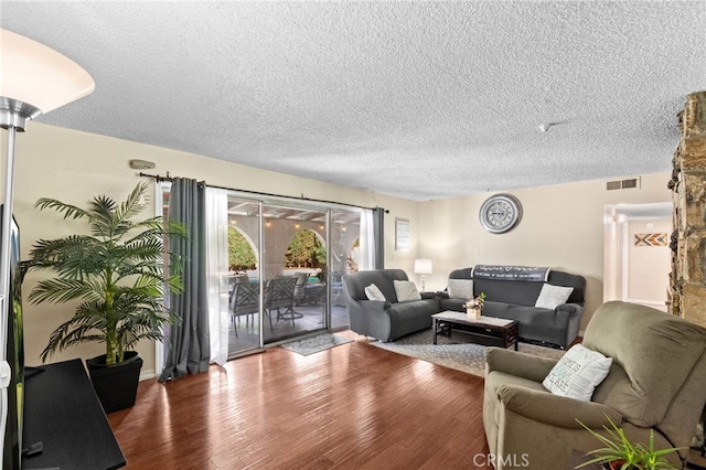 living room featuring a textured ceiling, visible vents, and wood finished floors