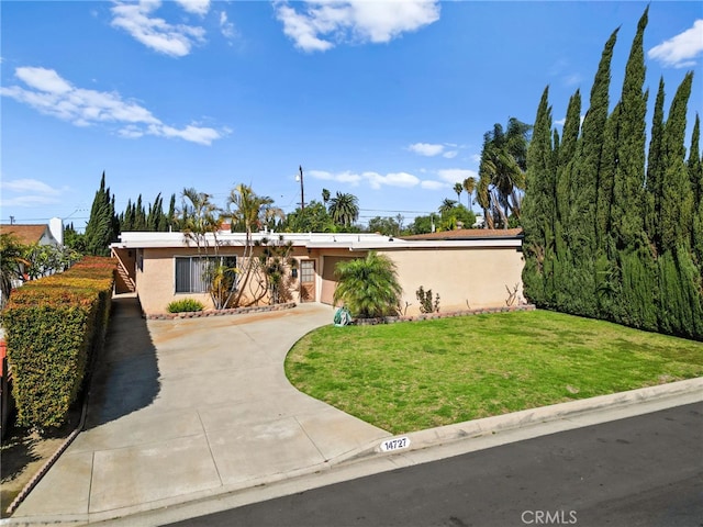 mid-century home featuring a front yard, concrete driveway, and stucco siding