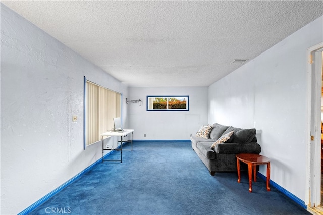 living area featuring a textured ceiling, visible vents, carpet flooring, and a textured wall