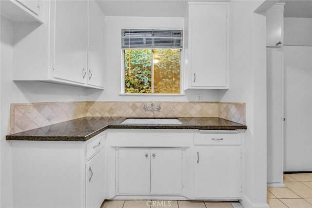 kitchen with white cabinets, a sink, decorative backsplash, and light tile patterned floors