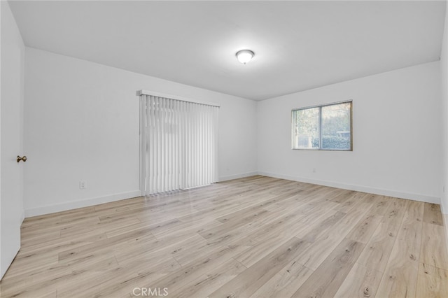 unfurnished room with light wood-style flooring and baseboards