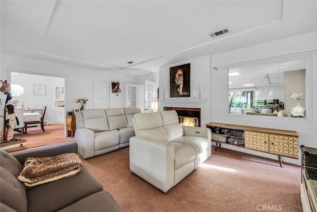 living room with carpet floors, a glass covered fireplace, and visible vents