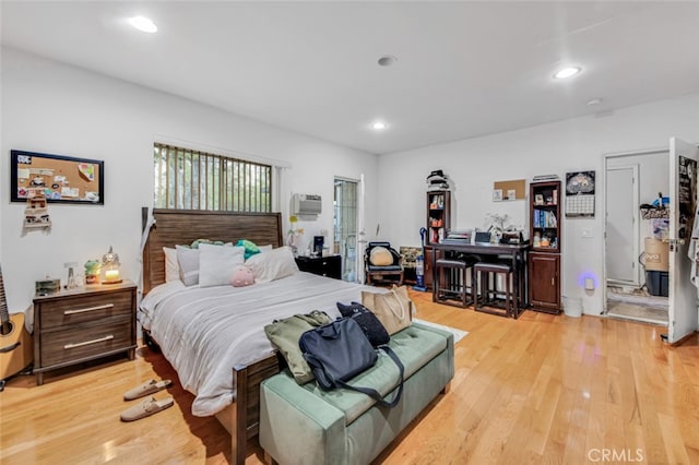 bedroom featuring light wood-style floors, an AC wall unit, and recessed lighting