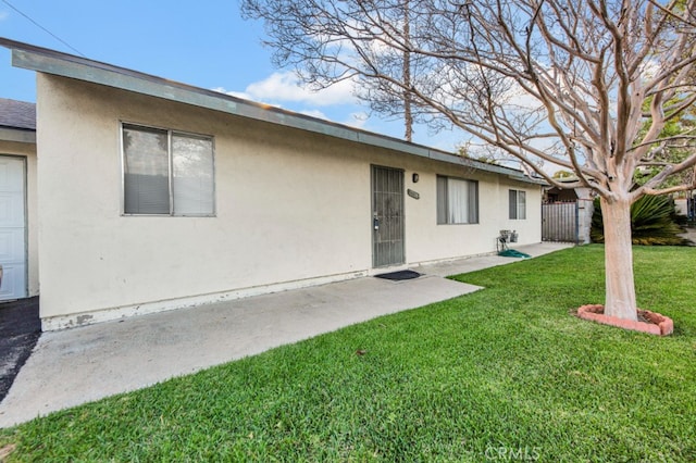 rear view of property featuring roof with shingles, a yard, fence, and stucco siding