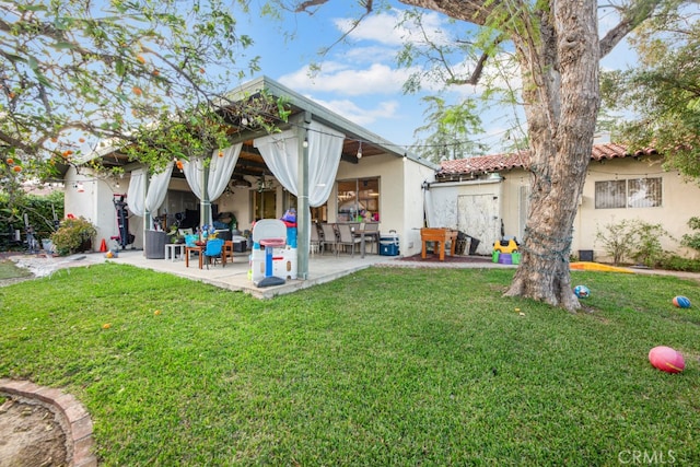 back of property with a patio area, a lawn, a tiled roof, and stucco siding