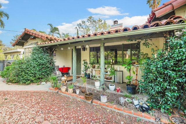 exterior space with a tile roof, a patio, a chimney, and stucco siding