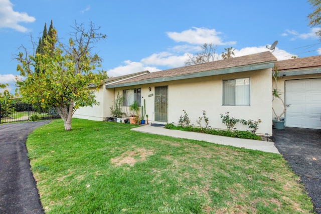 ranch-style house featuring an attached garage, fence, driveway, stucco siding, and a front lawn