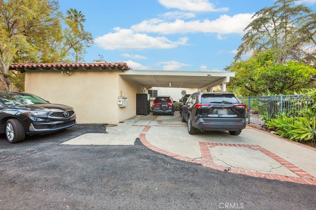 view of front of house with an attached carport, a tile roof, fence, driveway, and stucco siding