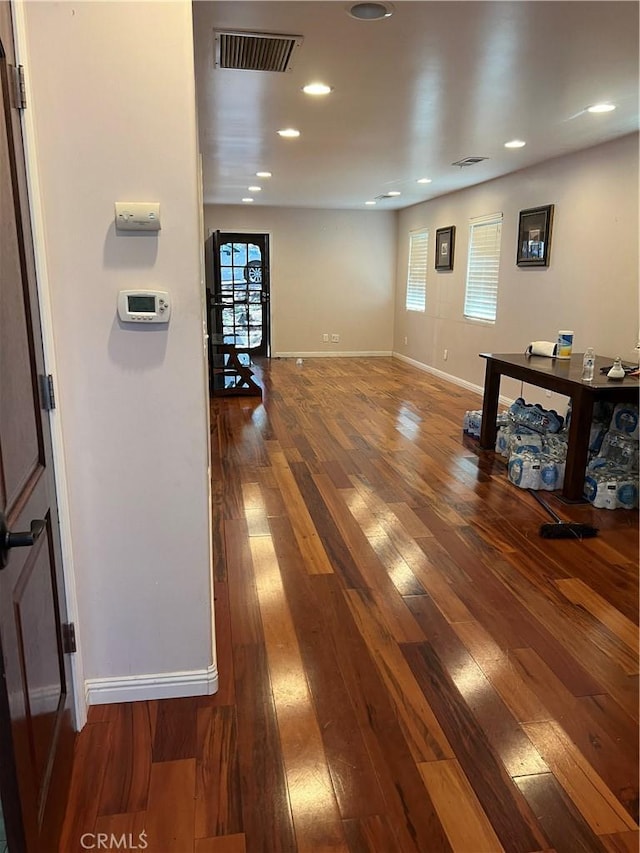 corridor with wood-type flooring, visible vents, baseboards, and recessed lighting