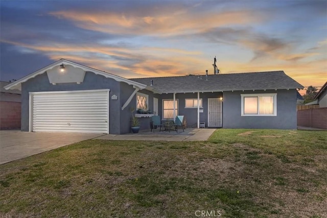 view of front of home with a garage, fence, driveway, a lawn, and stucco siding