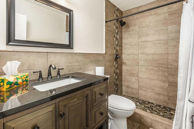 full bathroom featuring toilet, a stall shower, tile walls, and vanity