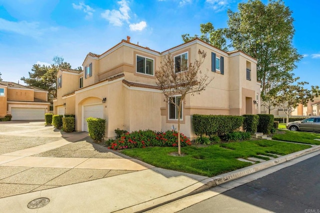 view of front of property with a garage, a front yard, driveway, and stucco siding