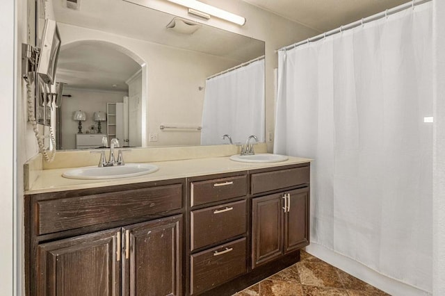 full bath with double vanity, stone finish flooring, and a sink