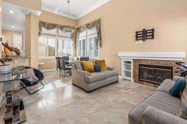 living room with baseboards, a chandelier, marble finish floor, crown molding, and a tile fireplace