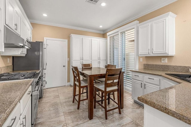 kitchen featuring high end stainless steel range, white cabinetry, crown molding, and under cabinet range hood