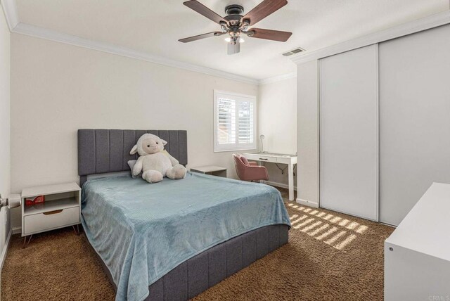 carpeted bedroom with baseboards, visible vents, a closet, ceiling fan, and ornamental molding