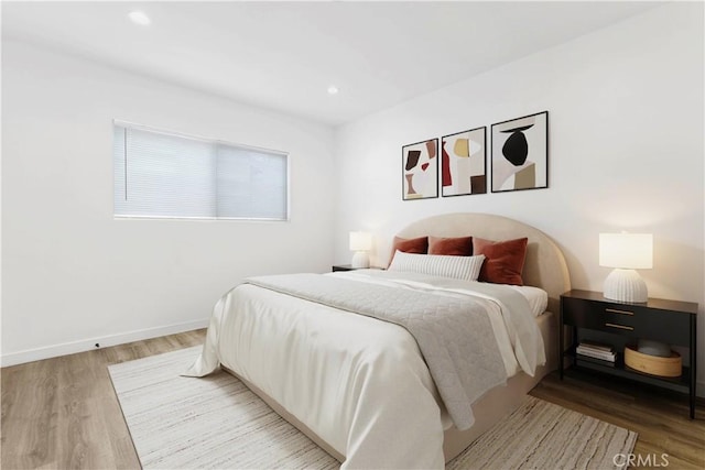 bedroom featuring baseboards, wood finished floors, and recessed lighting