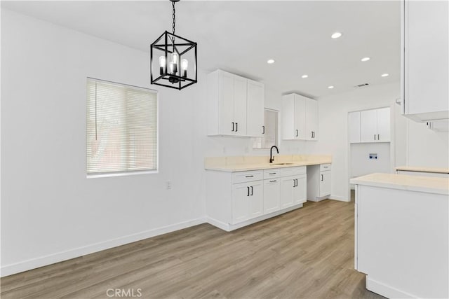 kitchen with light wood-style floors, baseboards, white cabinets, and a sink