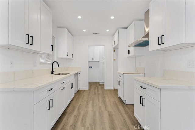 kitchen with light wood-style floors, recessed lighting, a sink, and light stone countertops