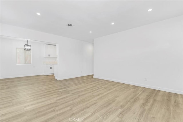 empty room with light wood-style flooring, recessed lighting, visible vents, and baseboards