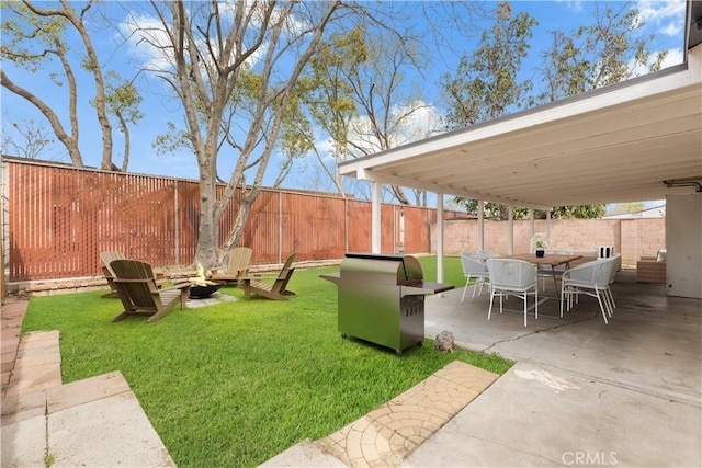 view of yard featuring a patio area, a fenced backyard, an outdoor fire pit, and outdoor dining space