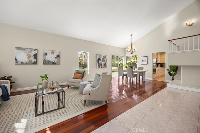 living room featuring high vaulted ceiling, baseboards, an inviting chandelier, and light tile patterned floors