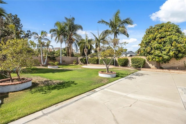 view of community with a patio area, a fenced backyard, and a yard