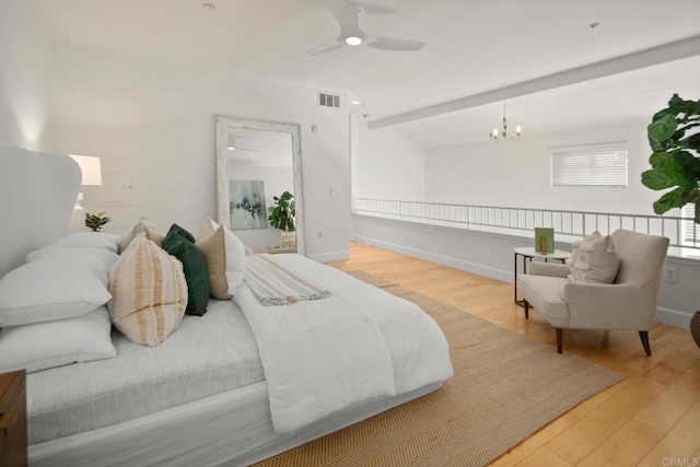 bedroom featuring ceiling fan with notable chandelier, visible vents, baseboards, and wood finished floors