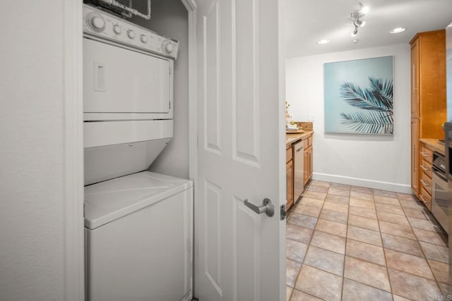 laundry room with laundry area, baseboards, and stacked washing maching and dryer