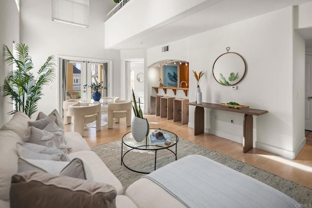 living room featuring visible vents, arched walkways, wood finished floors, and french doors