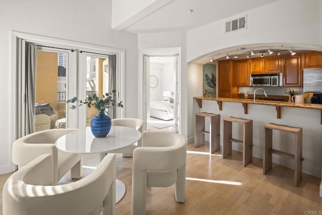 dining room with arched walkways, french doors, light wood finished floors, visible vents, and rail lighting