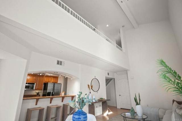 living area with a high ceiling, beamed ceiling, visible vents, and light wood-style floors