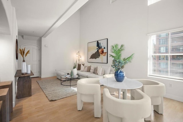 living room featuring a high ceiling, light wood-style flooring, and baseboards