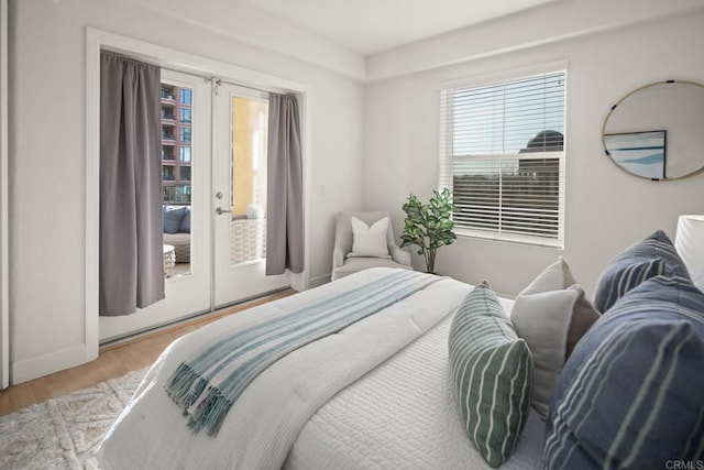 bedroom with access to outside, wood finished floors, and french doors